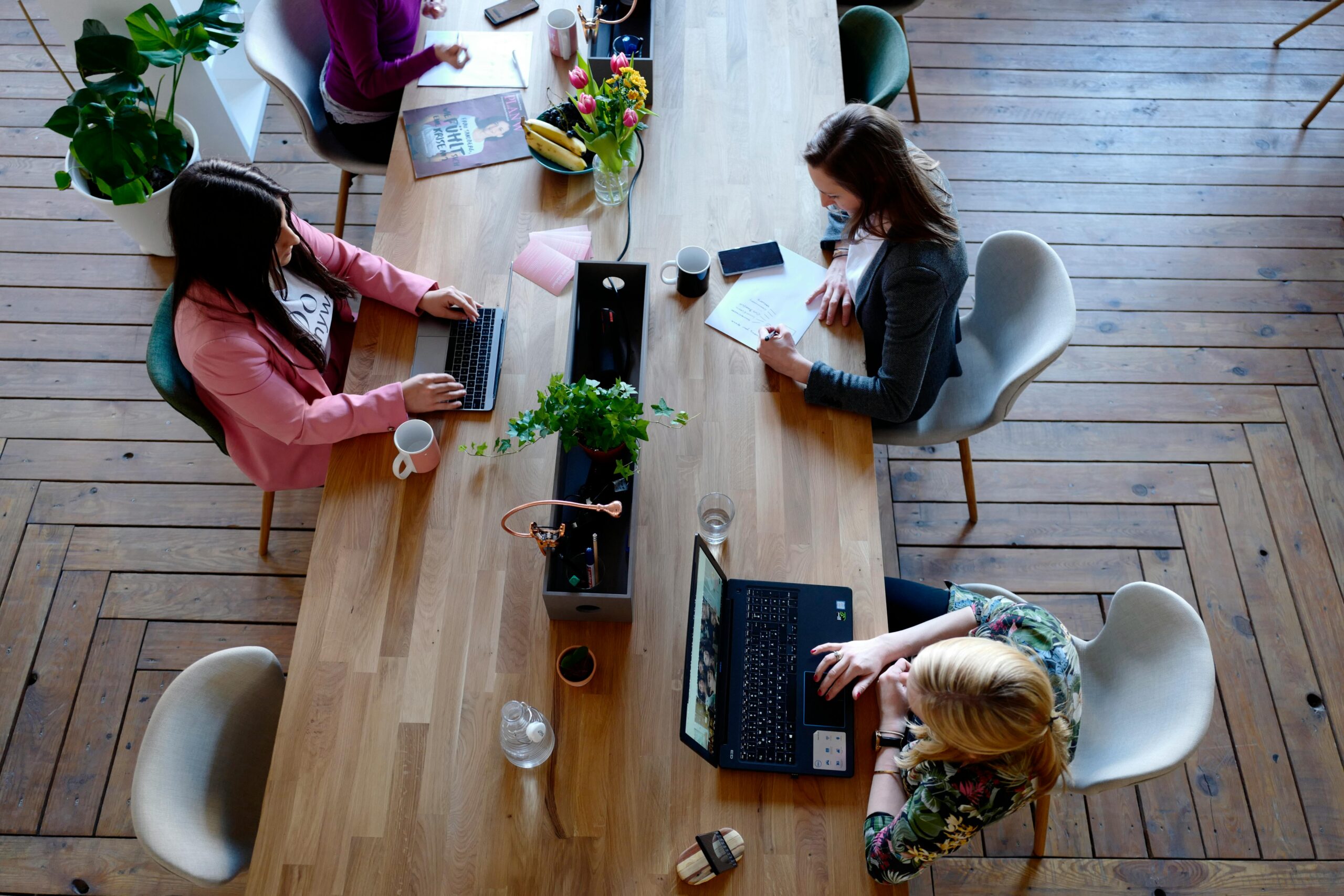 Women working at long table in co-working space.